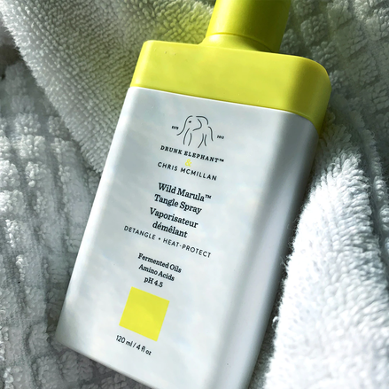 photo of a tangle spray bottle nestled in the folds of a white bath towel