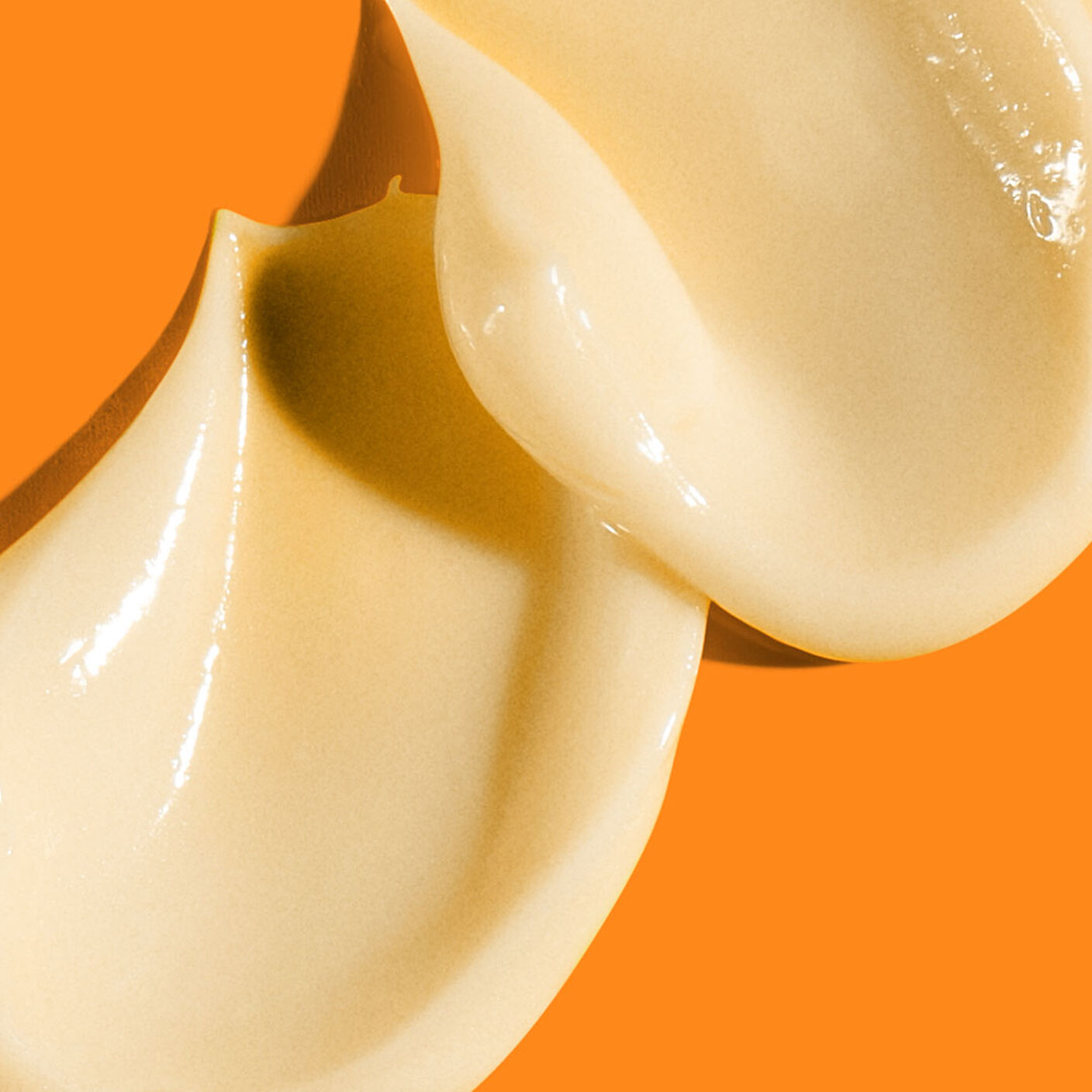 2 thick C-Tango Multivitamin Eye Cream  smears on a dark orange background. 