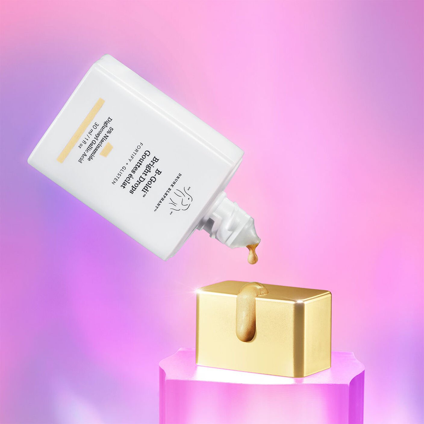    B-Goldi being poured on its cap that sits on an acrylic base in front of a pink background. 