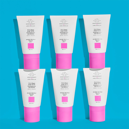 photograph of six scalp scrub bottles arrayed against a light blue background