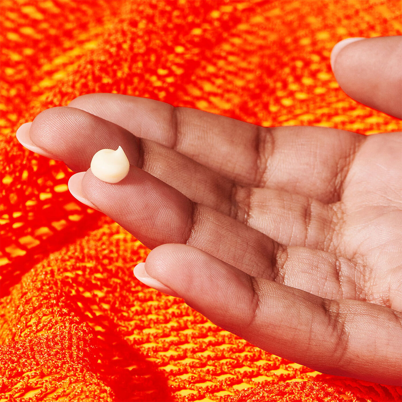 A hand with a droplet of the C-Tango Multivitamin Eye Cream cream on the tip of a finger. 
