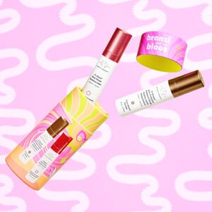 8ml of D-Bronzi and 8ml of O-Bloos coming out of Bronzi and Bloos cylindrical packaging in front of light pink swirly background.