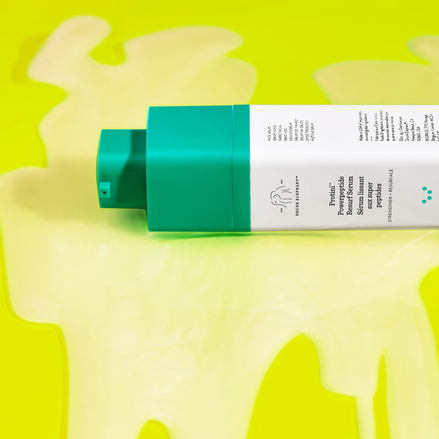photo of Protini Serum bottle laying out in goop shot of product against yellow background