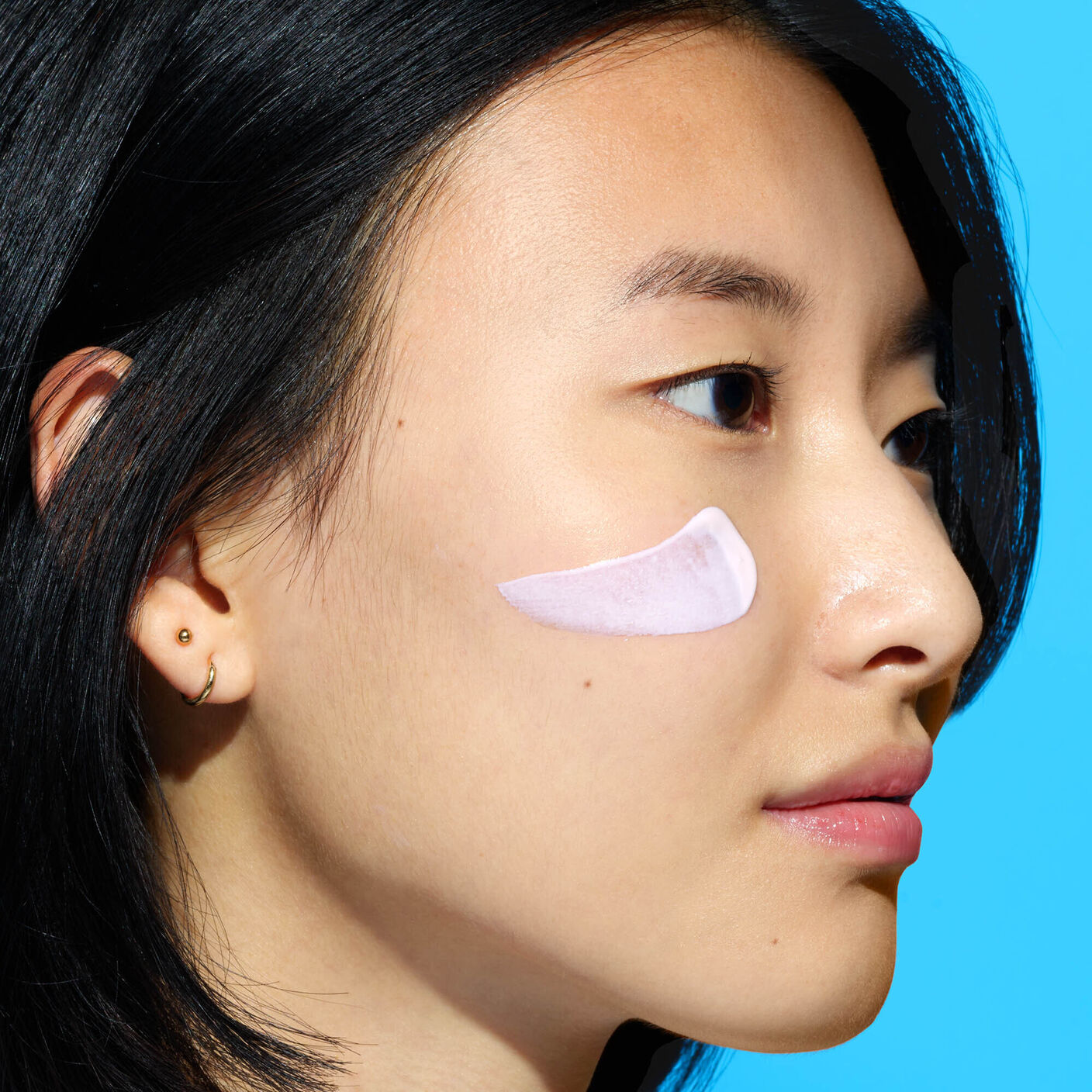 Umbra Sheer Mineral Cream smear on the side of womans face. 
