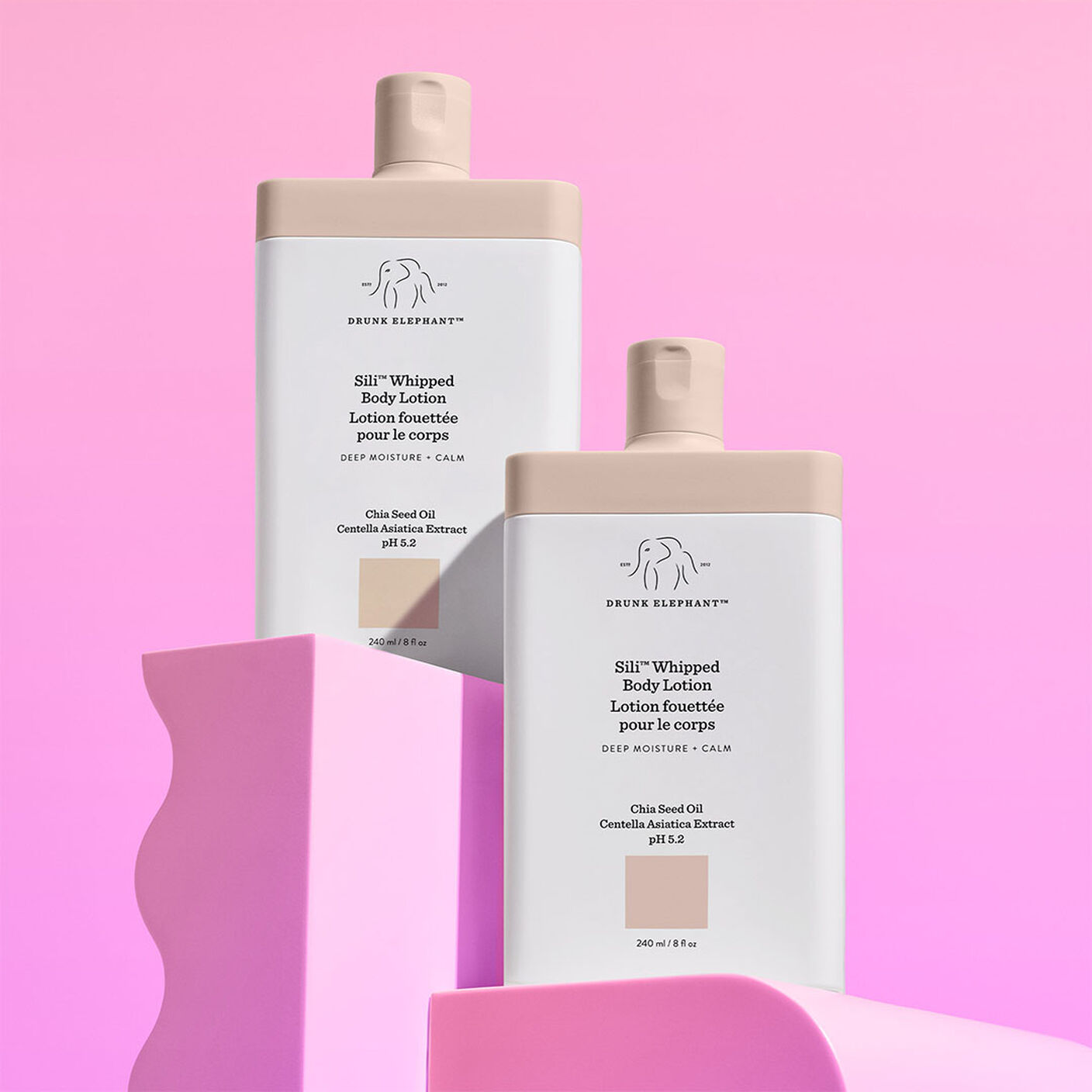 Two Sili Whipped Body Lotion Bottles stacked on pink acrylic prop. 