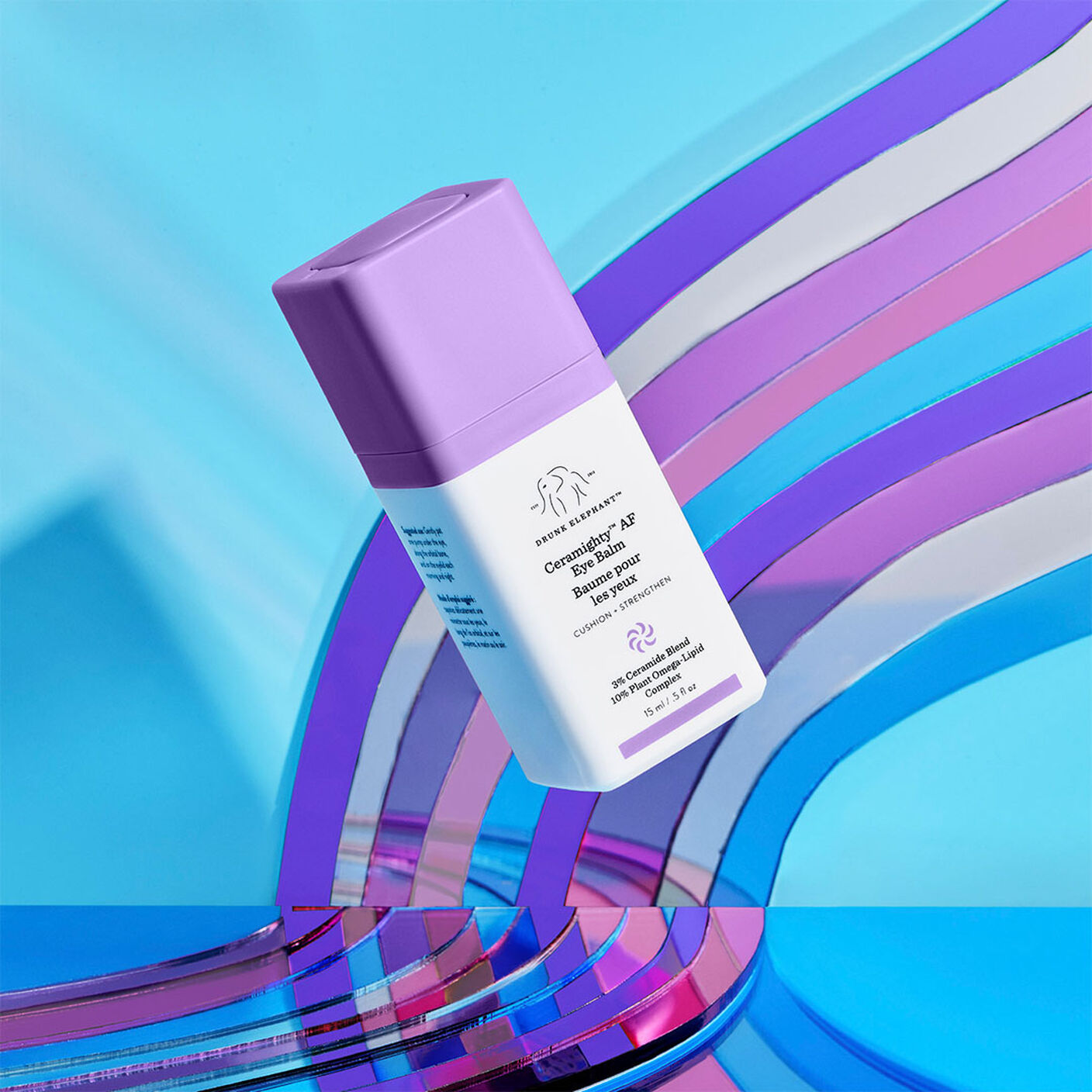 Creamighty AF Eye Balm floating in front of an acrylic prop of different shades of purple. 