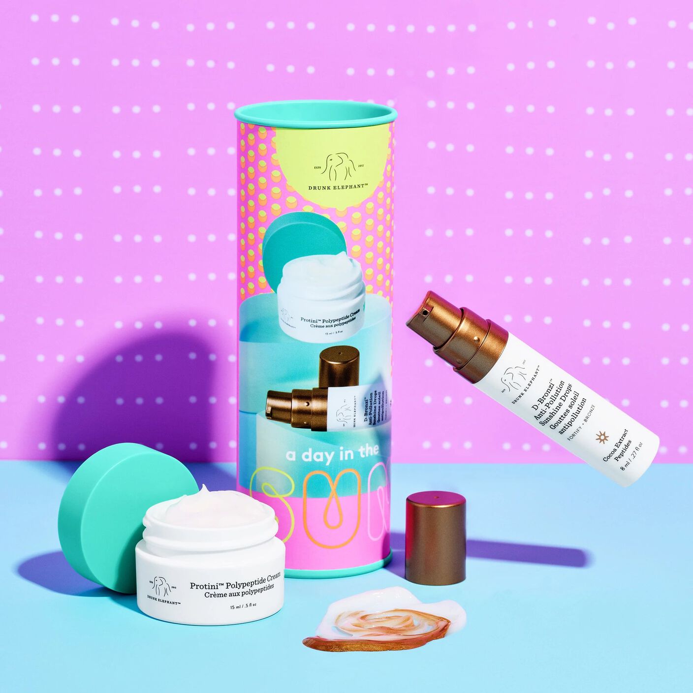 Floating D-Bronzi (8ml) and Protini Cream (15ml) with the caps off and a mixed smear of the serum and cream beside them. 