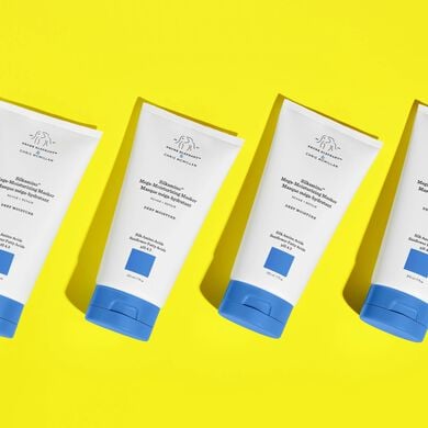 Multiple bottles of Silkamino Mega-Moisturizing Masker laid flat diagonally on top of a yellow background