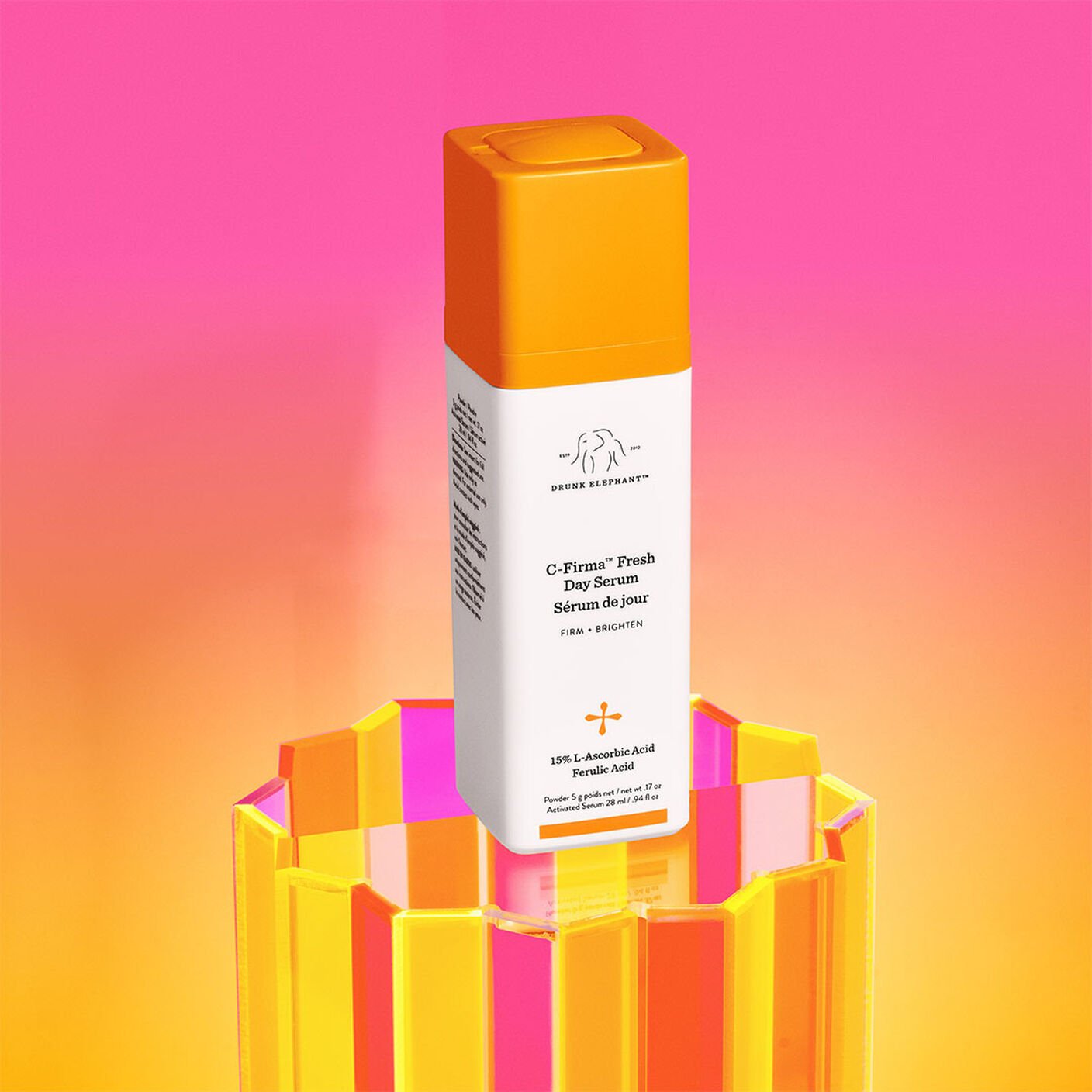 C-Firma bottle on an acrylic stand behind a pink and orange background. 