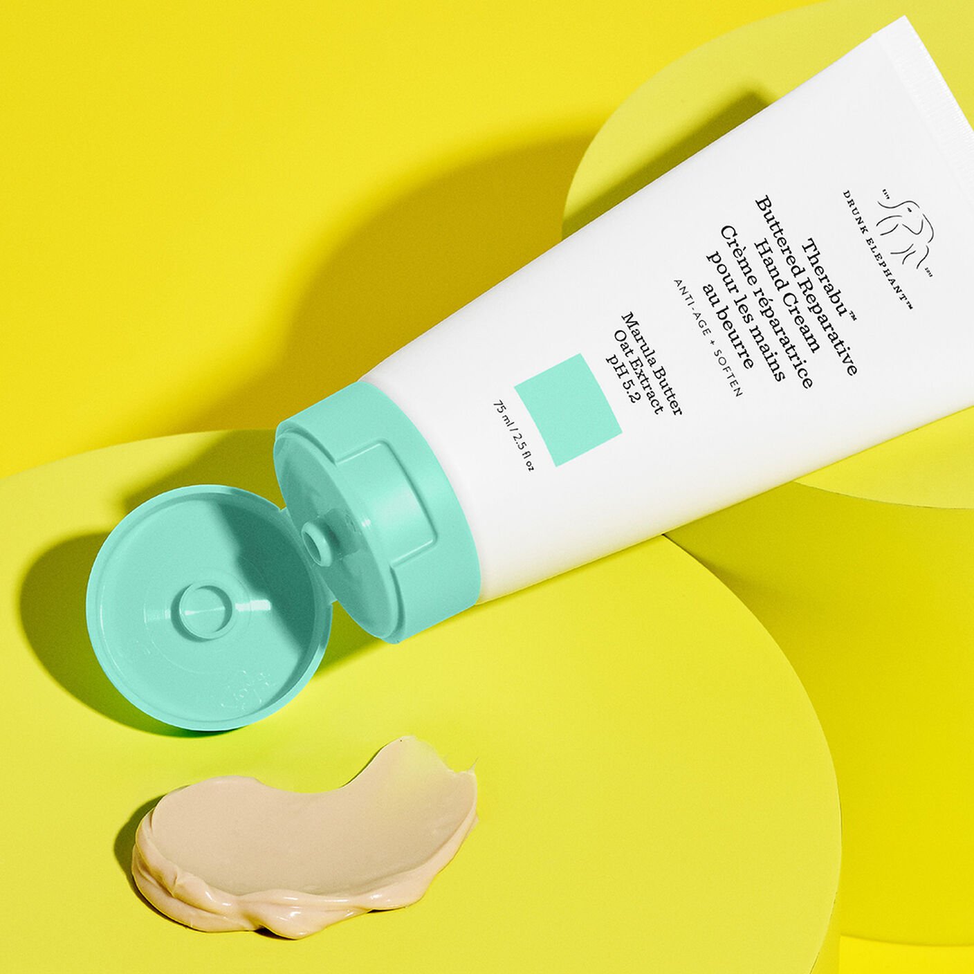 Texture shot of Therabu hand cream smear on yellow platform with Therabu tube beside it. 