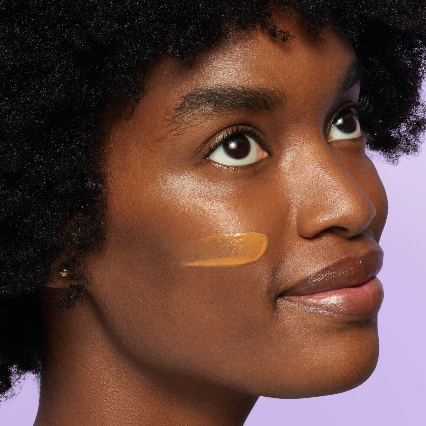 Umbra Cocoa Mineral Cream smear on the side of woman's face.