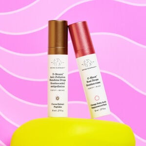 8ml of D-Bronzi and 8ml of O-Bloos on a yellow prop in front of a dark pink and light pink wavey designed background.