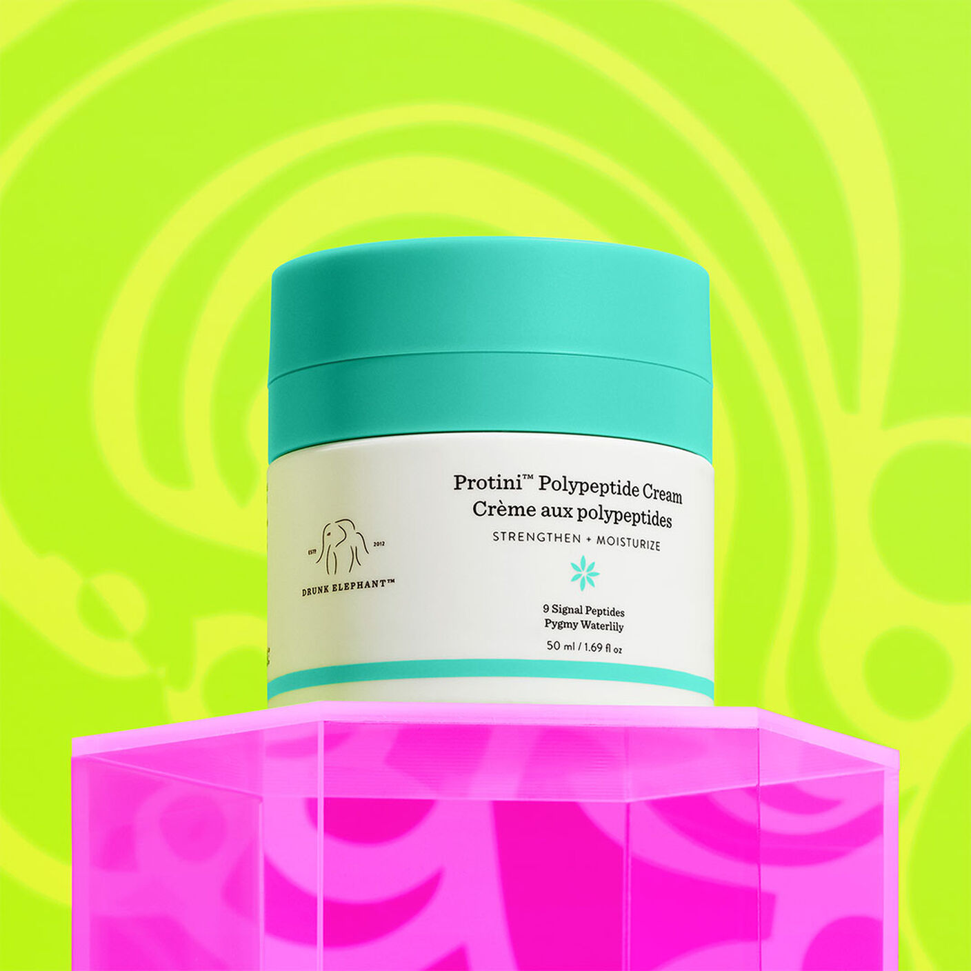  Protini Cream container on top of a pink acrylic stand on a yellow and green background. 