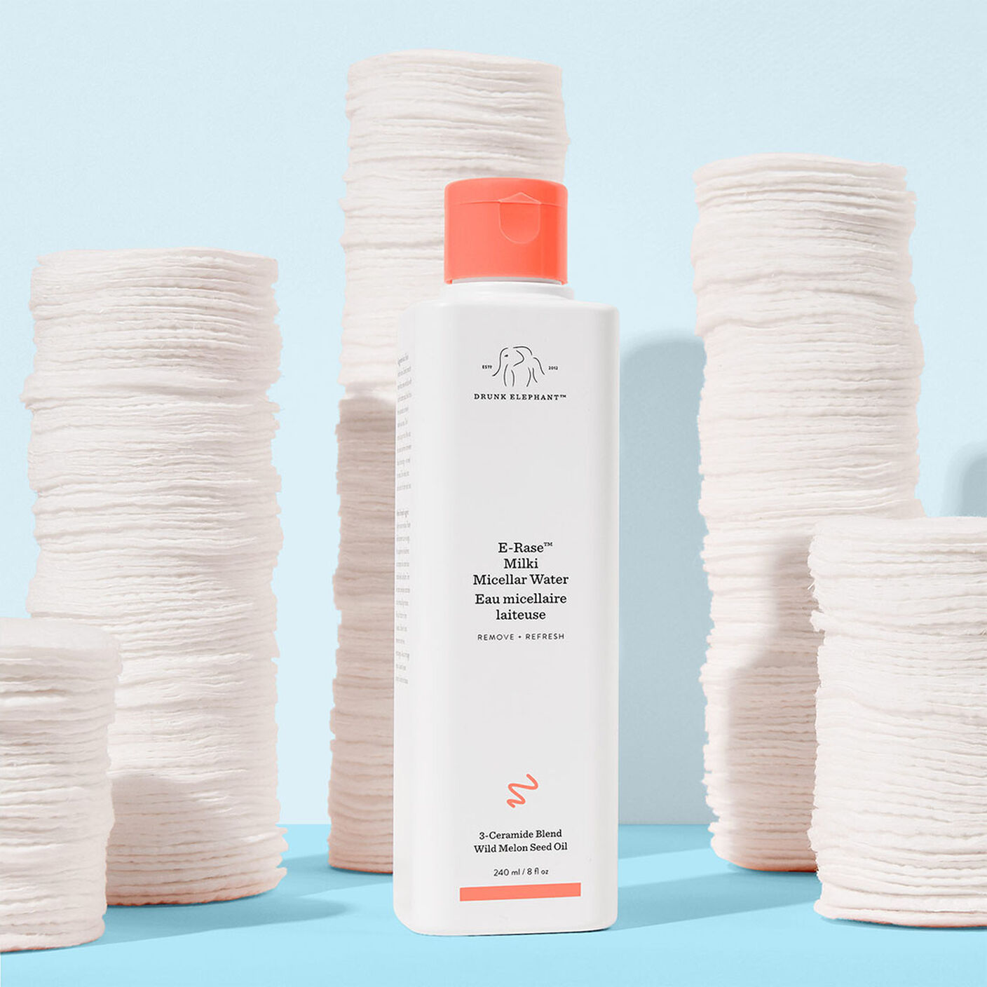 E-Rase Milki Micellar Water next to stacks of cotton pads. 