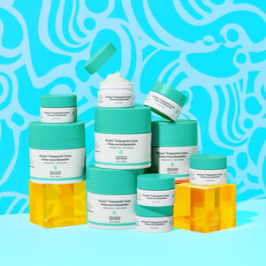 photo of multiple Protini full size and littles contatiners stacked on top of each other, one open showing teh cream, some sitting on acryclic boxes, all against a designed blue background
