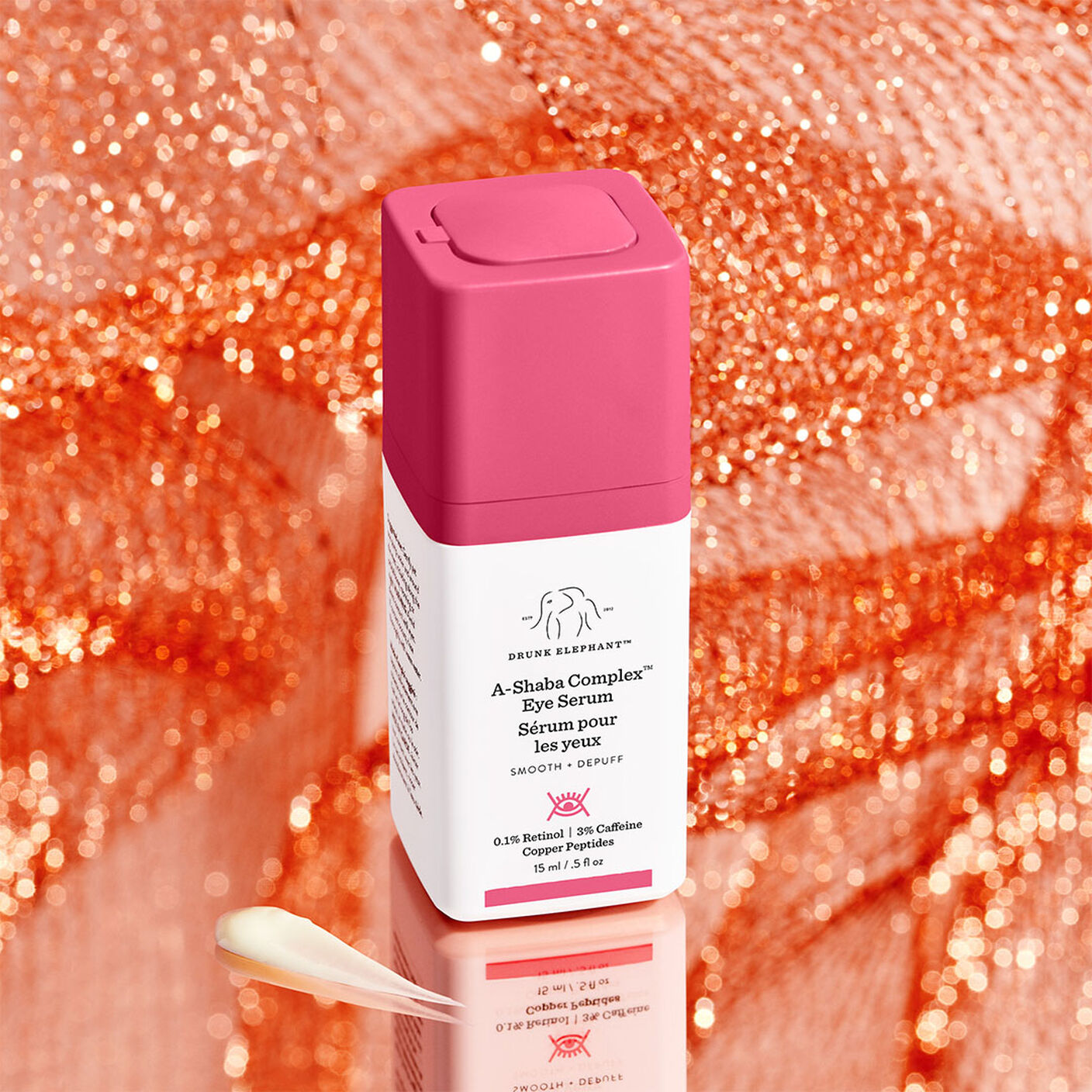 A-Shaba Complex Eye Serum in front of an orange sparkling background next to a smear of product.
