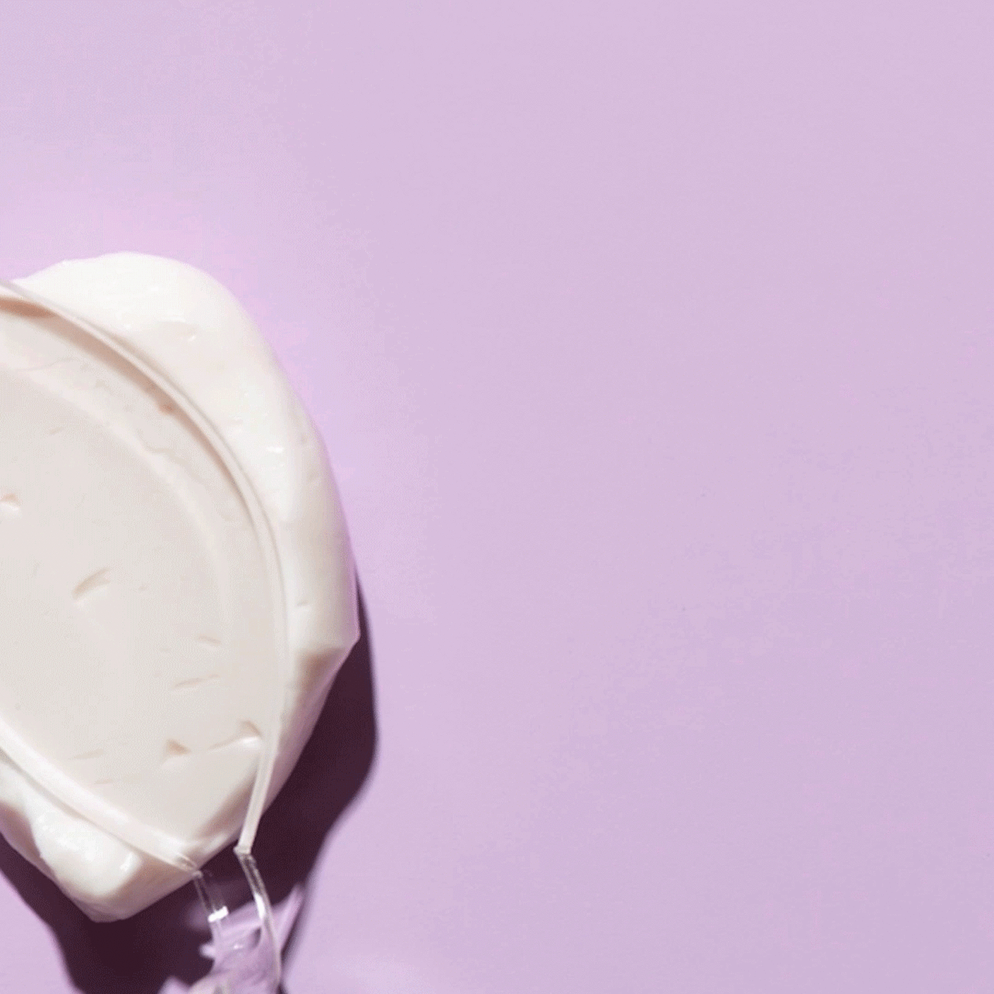 GIF of Creamighty AF Eye Balm being smeared with a clear spatula across a llight purple background. 
