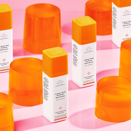 Image of C-Firma Fresh bottles standing next to orange props against a pink background