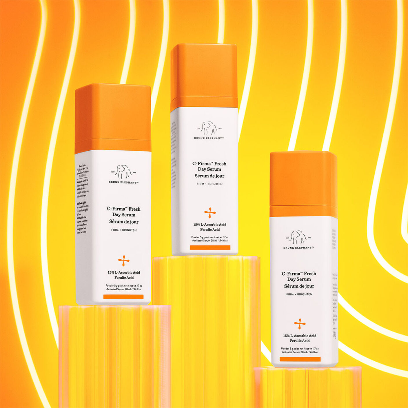 3 C-firma bottles on acrylic stands behind an orange striped wavey background. 