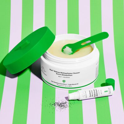 Three Slaai™ Makeup-Melting Butter Cleansers stacked on each other with the Slaai spoon sticking up inside the product of an open container