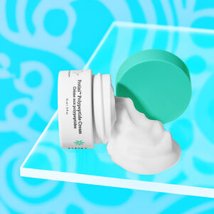 photo of a Protini littles laid flat on a clear acryclic top with cream pouring out, against a designed blue background